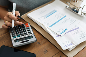 Hand resting on calculator alongside paper documents